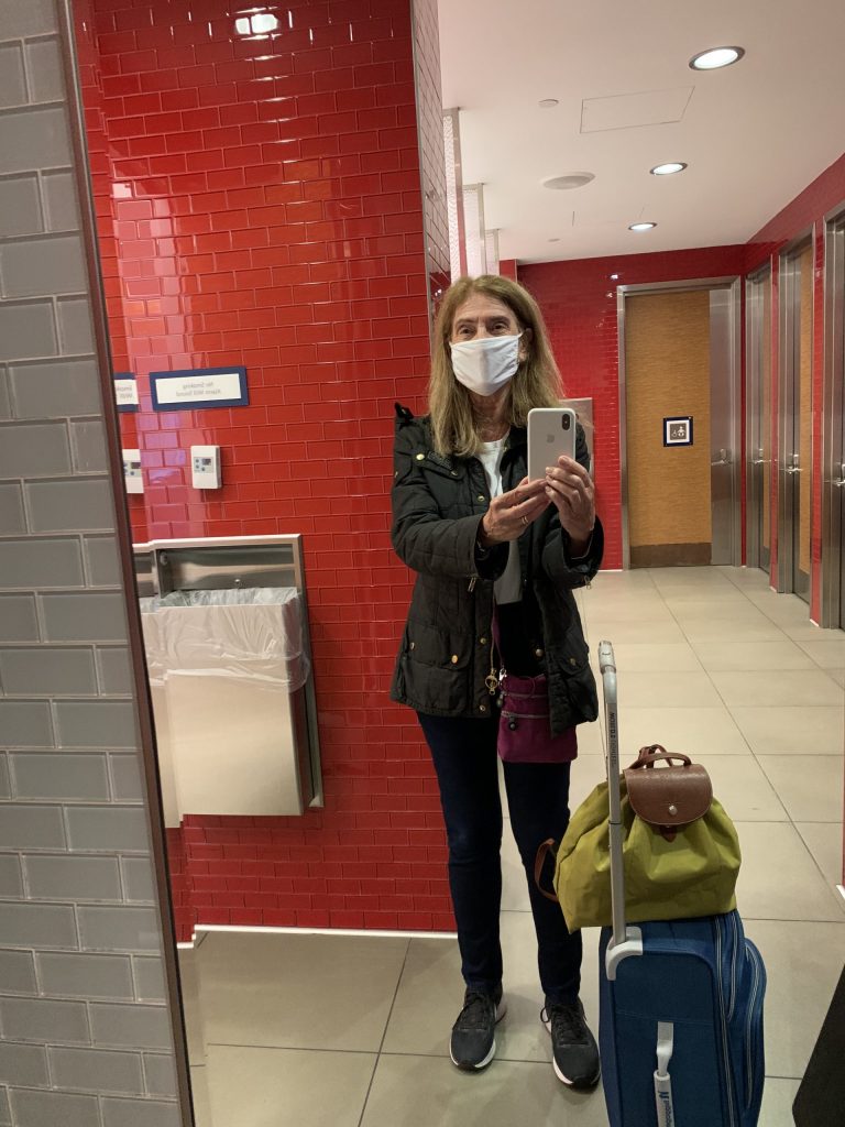 Boomers Busted or Traveling Boomer, Phyllis Stoller masked at JFK showing common sense protocols about travel.